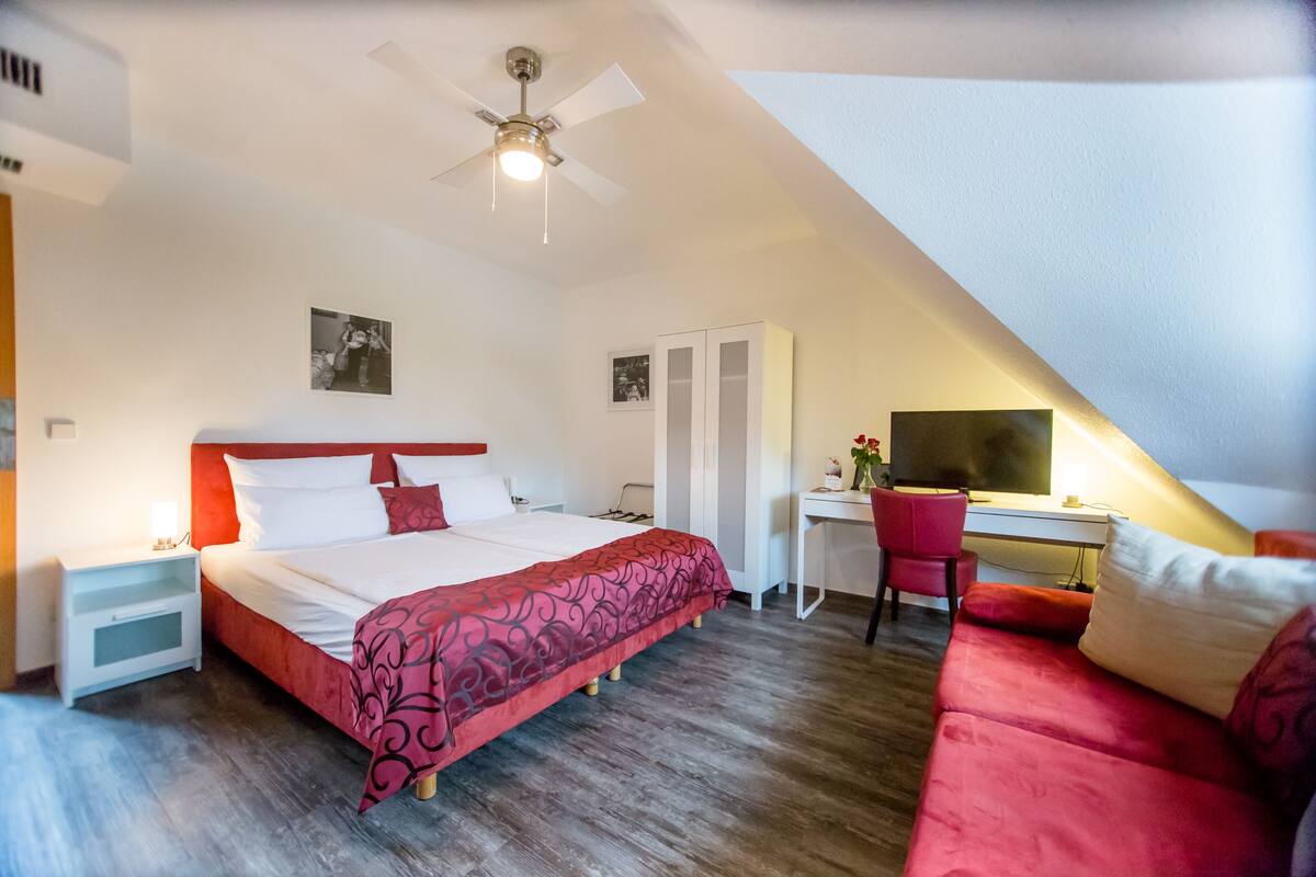 Un dormitorio con una cama, un escritorio, una silla y un sofá rojo.