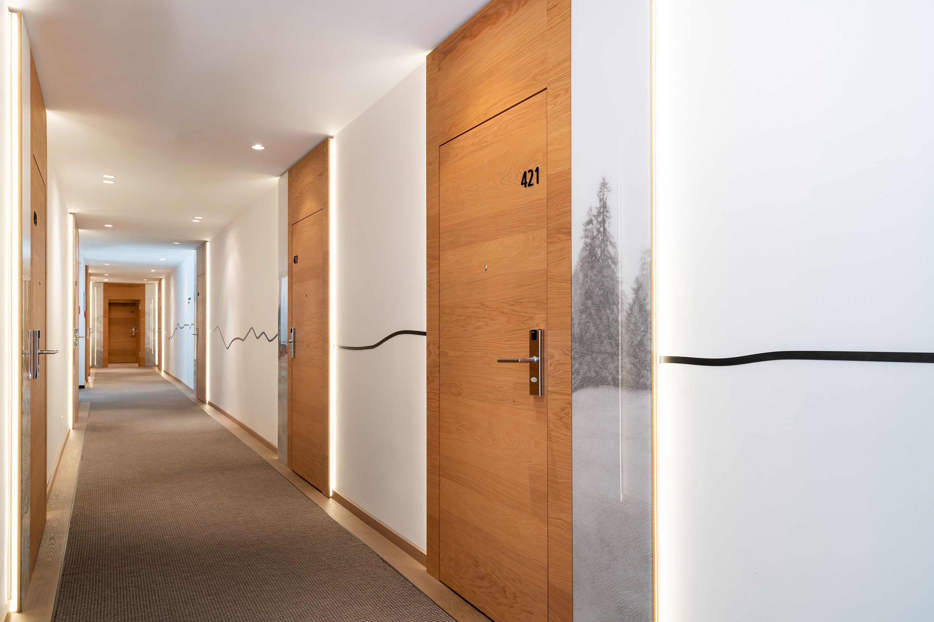 Un pasillo moderno de hotel con puertas de madera, número 421, y suelo alfombrado.