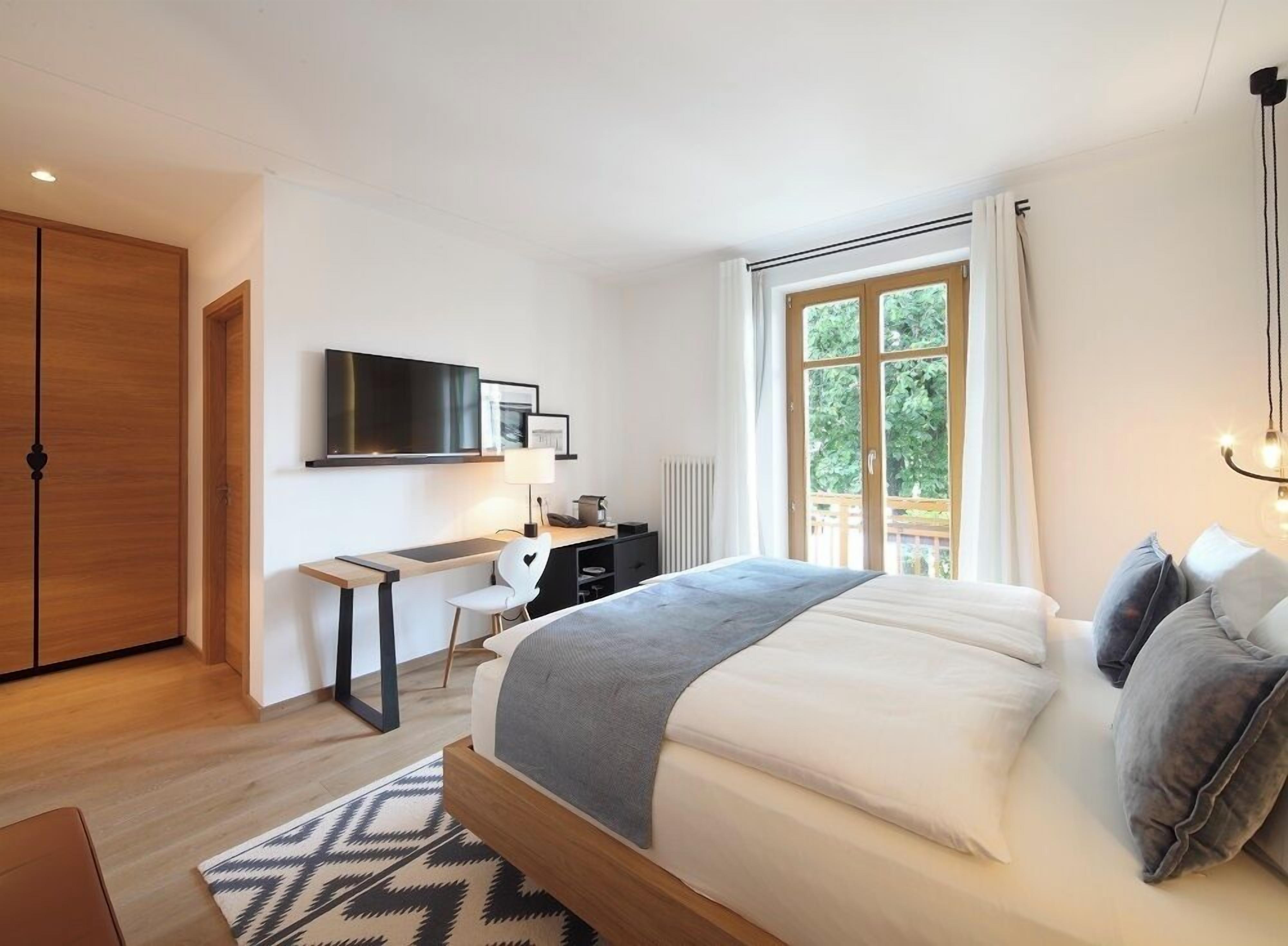 Un dormitorio moderno con una cama grande, un escritorio, una silla y un televisor.