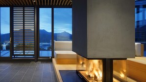 A modern interior with a fireplace, large windows, and a view of mountains. - Das Tegernsee (Tegernsee)