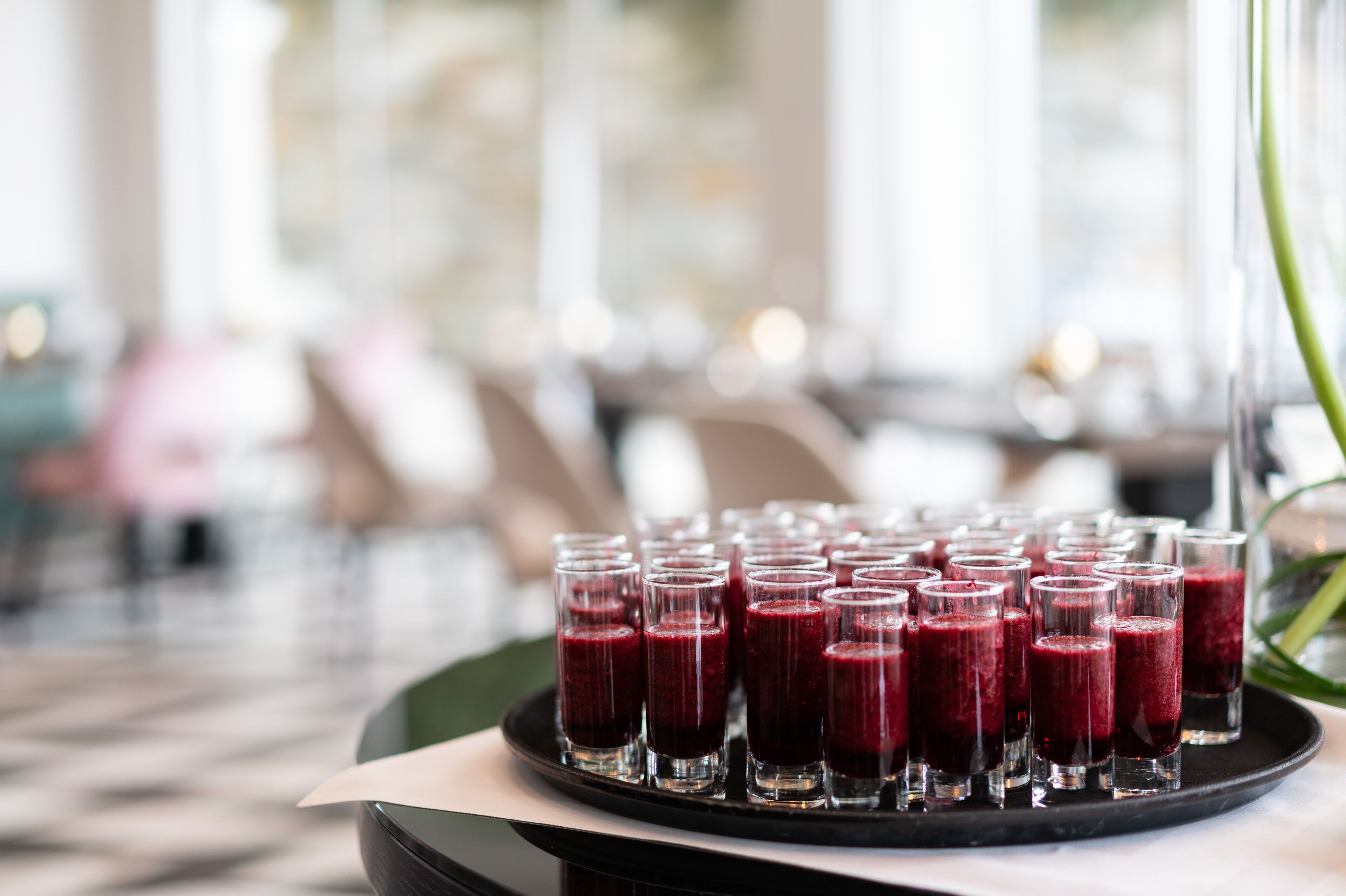 A tray of red smoothies on a table in a well-lit indoor setting.