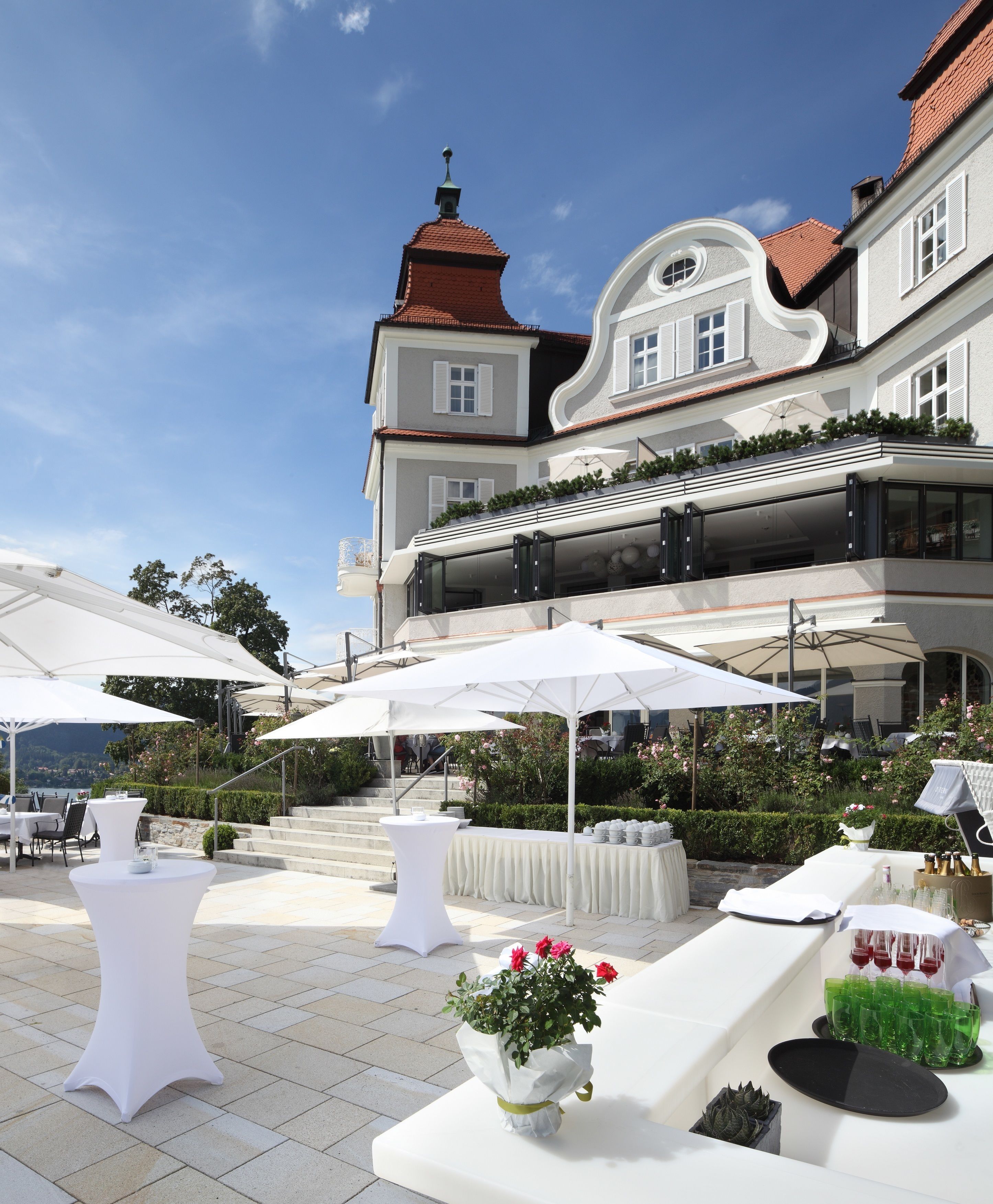 Une cour avec des espaces de repos en plein air, des parasols et un bâtiment dont le toit est recouvert de tuiles rouges.