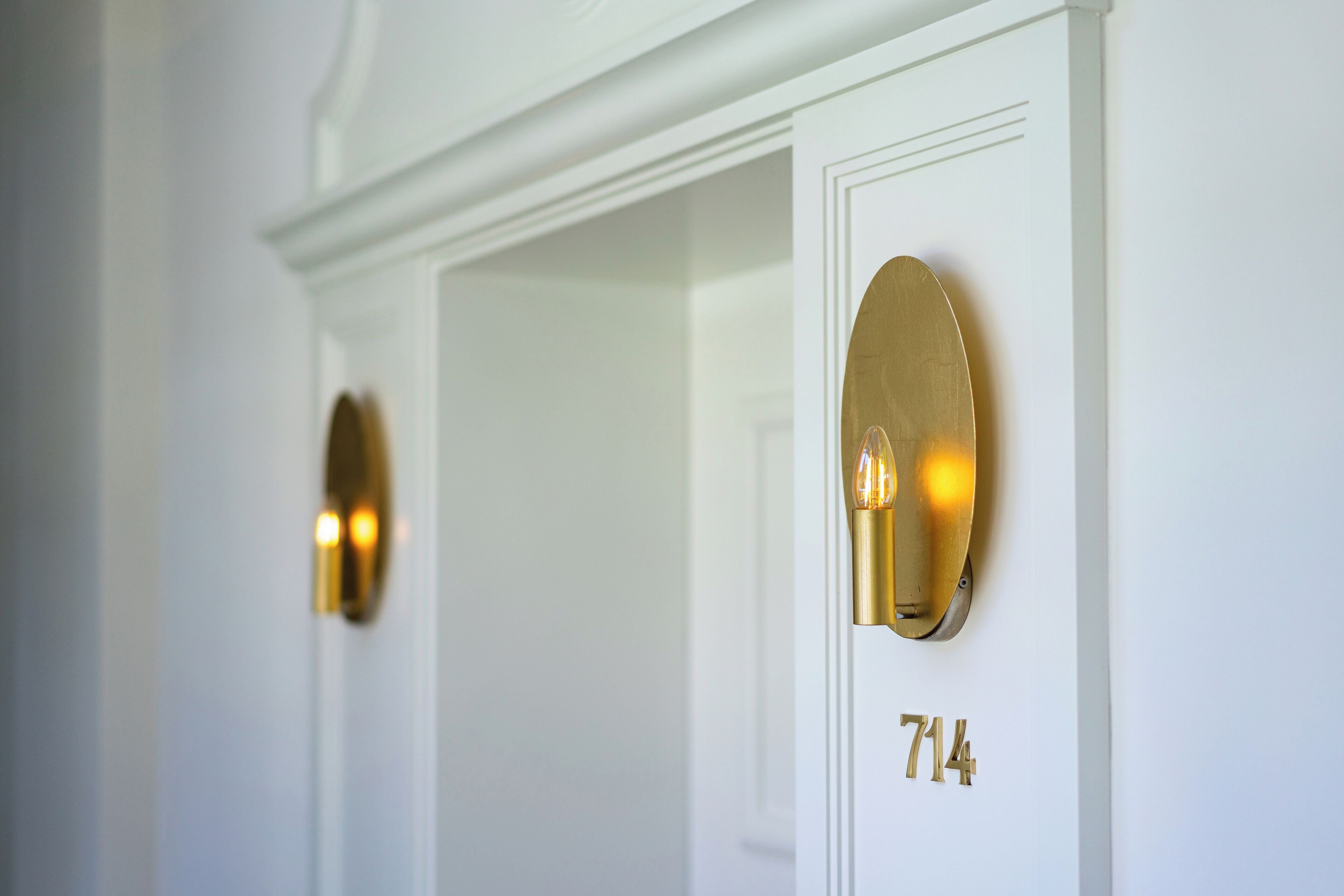 Eine weiße Tür mit einer goldenen Nummertafel, auf der Zimmer 714 steht.
