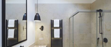 Un baño moderno con un espejo grande, dos barras para toallas, ducha con cerramiento de vidrio y techo de madera.