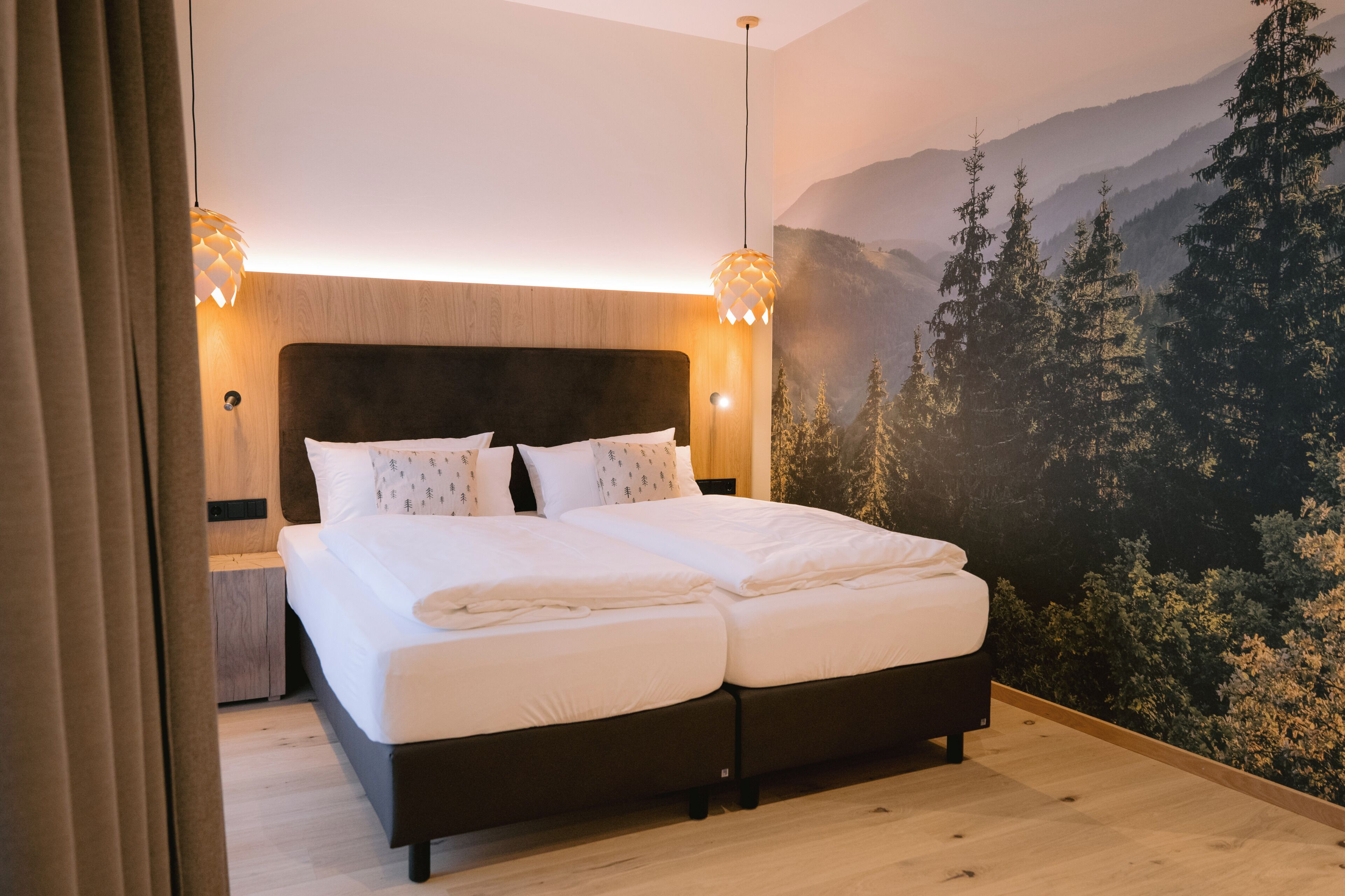 Ein Doppelbett mit weißer Bettwäsche, ein dunkles Kopfteil und zwei Wandlampen.