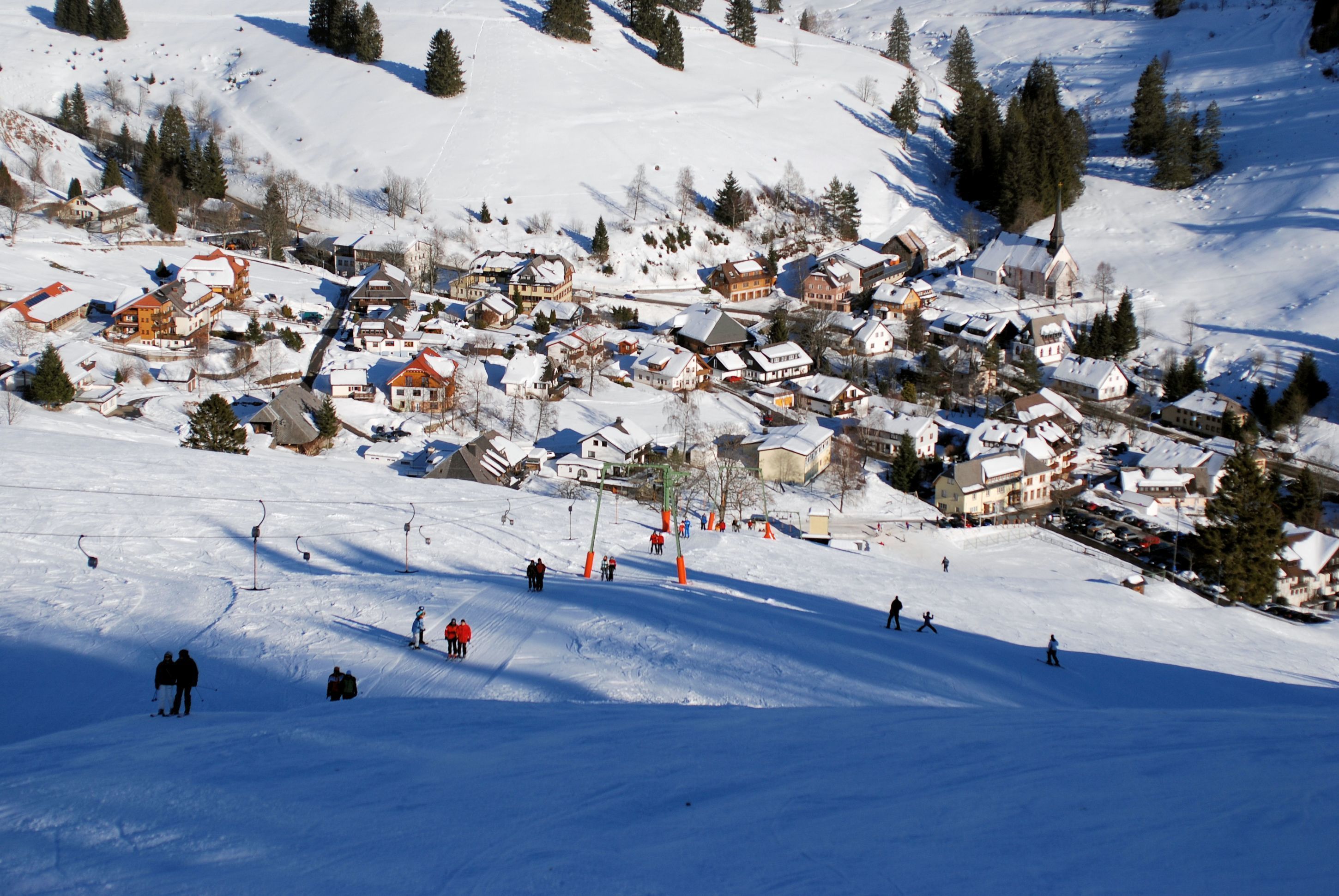 A snow-covered village with buildings and a ski slope.