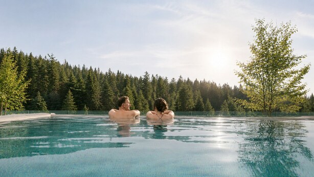 Une piscine où se trouvent deux personnes, entourée d’arbres.