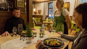 A dining table with a plate of food, wine glasses, and a small Christmas tree decoration.
