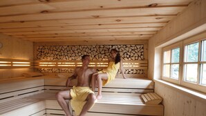Un sauna avec des bancs en bois et un mur en pierre.