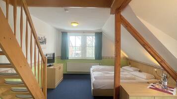 Une chambre avec un escalier en bois, un lit, un bureau et une fenêtre avec des rideaux.