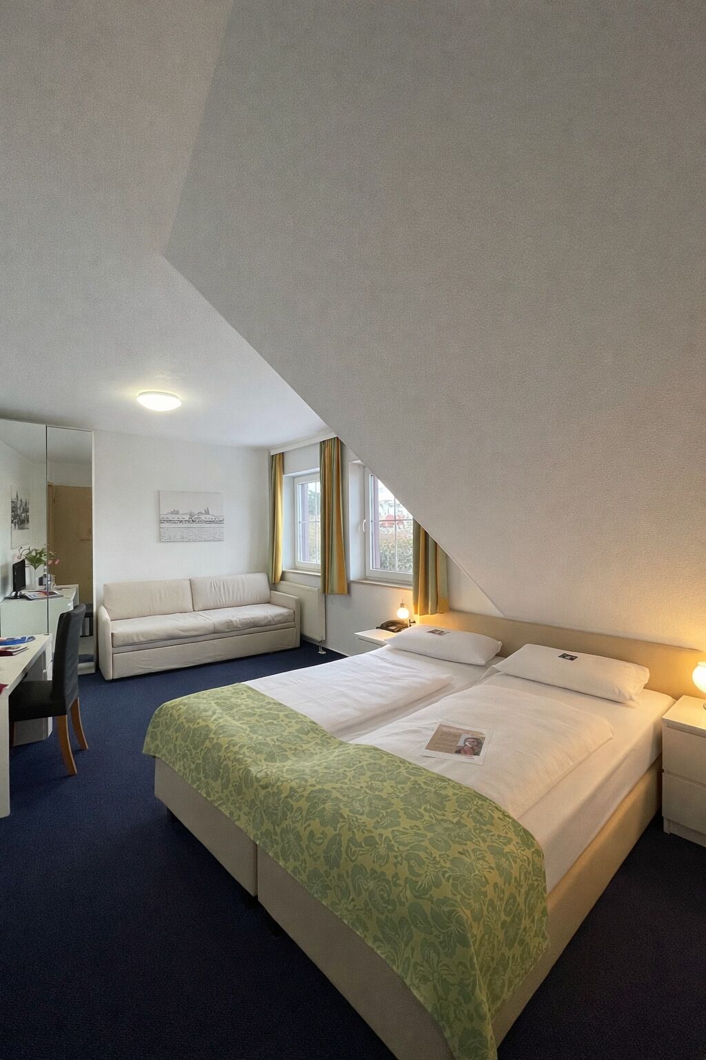 Una habitación de hotel con una cama grande, un escritorio, una silla y un sofá.