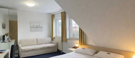 Una habitación de hotel con una cama grande, un escritorio, una silla y un sofá.
