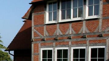 Ett traditionellt hus med korsvirkesfasad, rött tegeltak och många fönster.