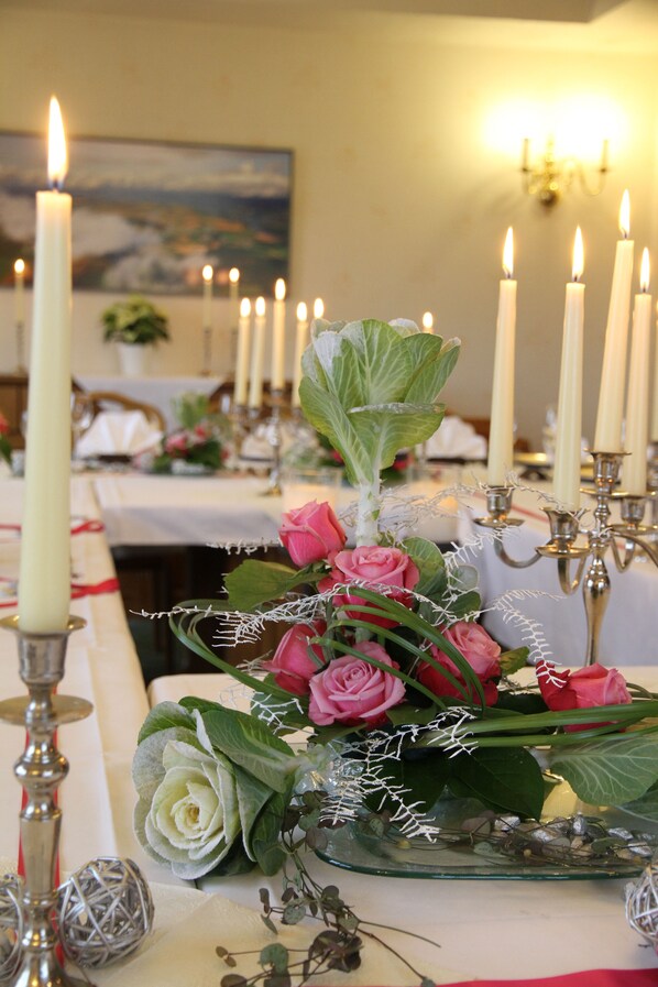 Una mesa decorada con velas, un florero de vidrio con rosas y un candelabro.