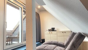 Une chambre de style loft moderne, dotée d’une grande fenêtre, d’un canapé incurvé et d’une armoire intégrée.