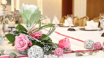 Una mesa dispuesta para comer con rosas rosadas, adornos esféricos blanco y rosa, y una cinta roja.