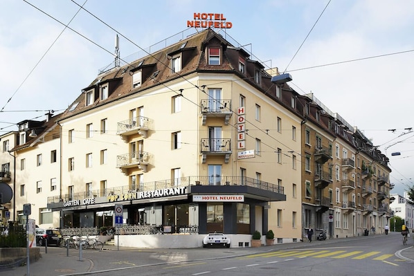 A hotel with a sign reading "HOTEL NEUFELD" and a restaurant named "GARTEN CAFÉ" below it. - Hotel Neufeld (Zürich)