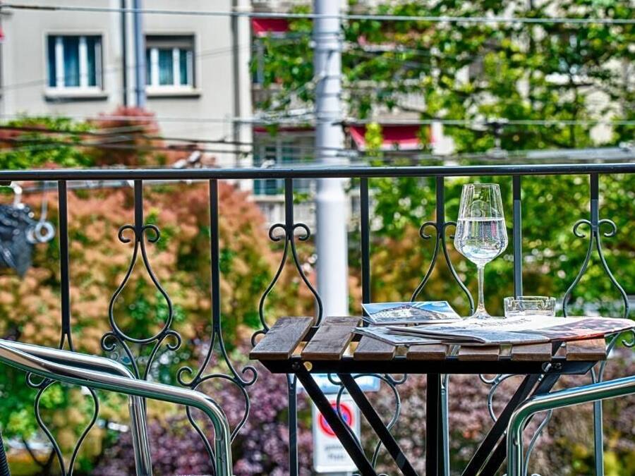 A balcony with a table set for two, featuring a glass of water and a menu.