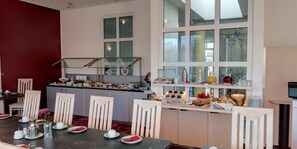 A modern kitchen with a central island, white cabinetry, and a dining area with a table set for four.