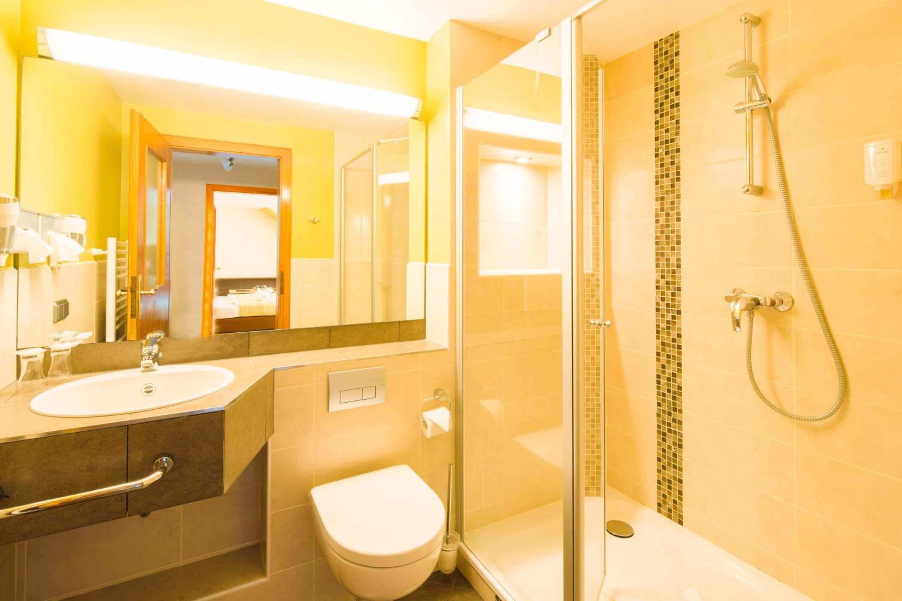 A bathroom with a glass shower enclosure, a white sink, and a toilet.