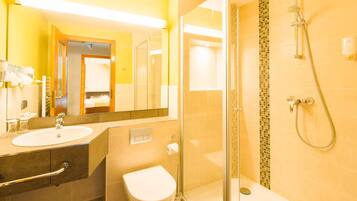 A bathroom with a glass shower enclosure, a white sink, and a toilet.