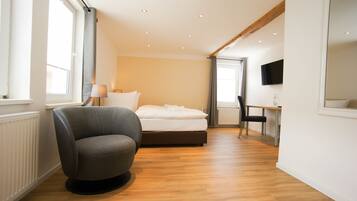Ein modernes Hotelzimmer mit Bett, Schreibtisch, Stuhl und Fernseher.