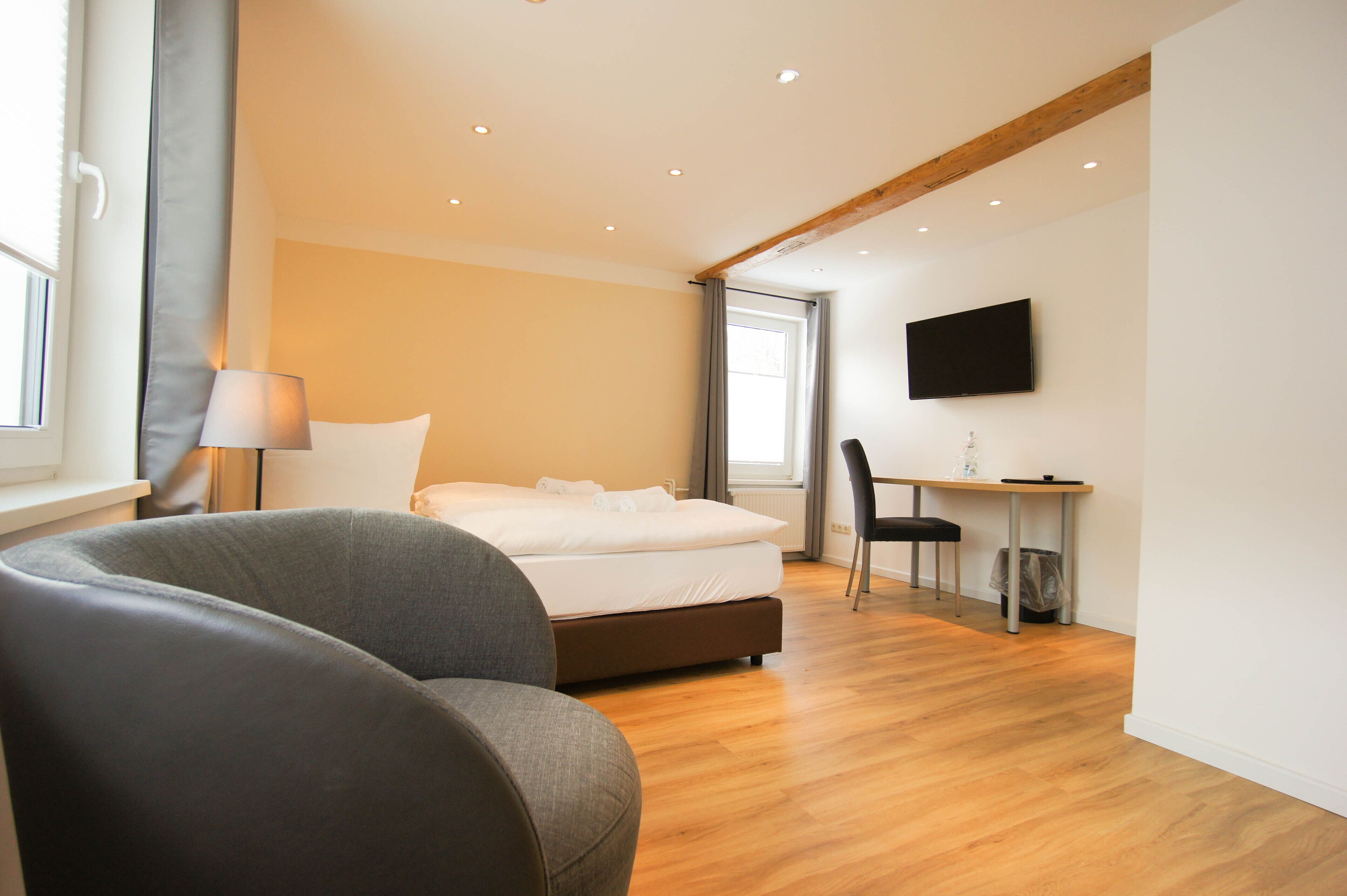 A modern bedroom with a bed, a desk, and a TV.