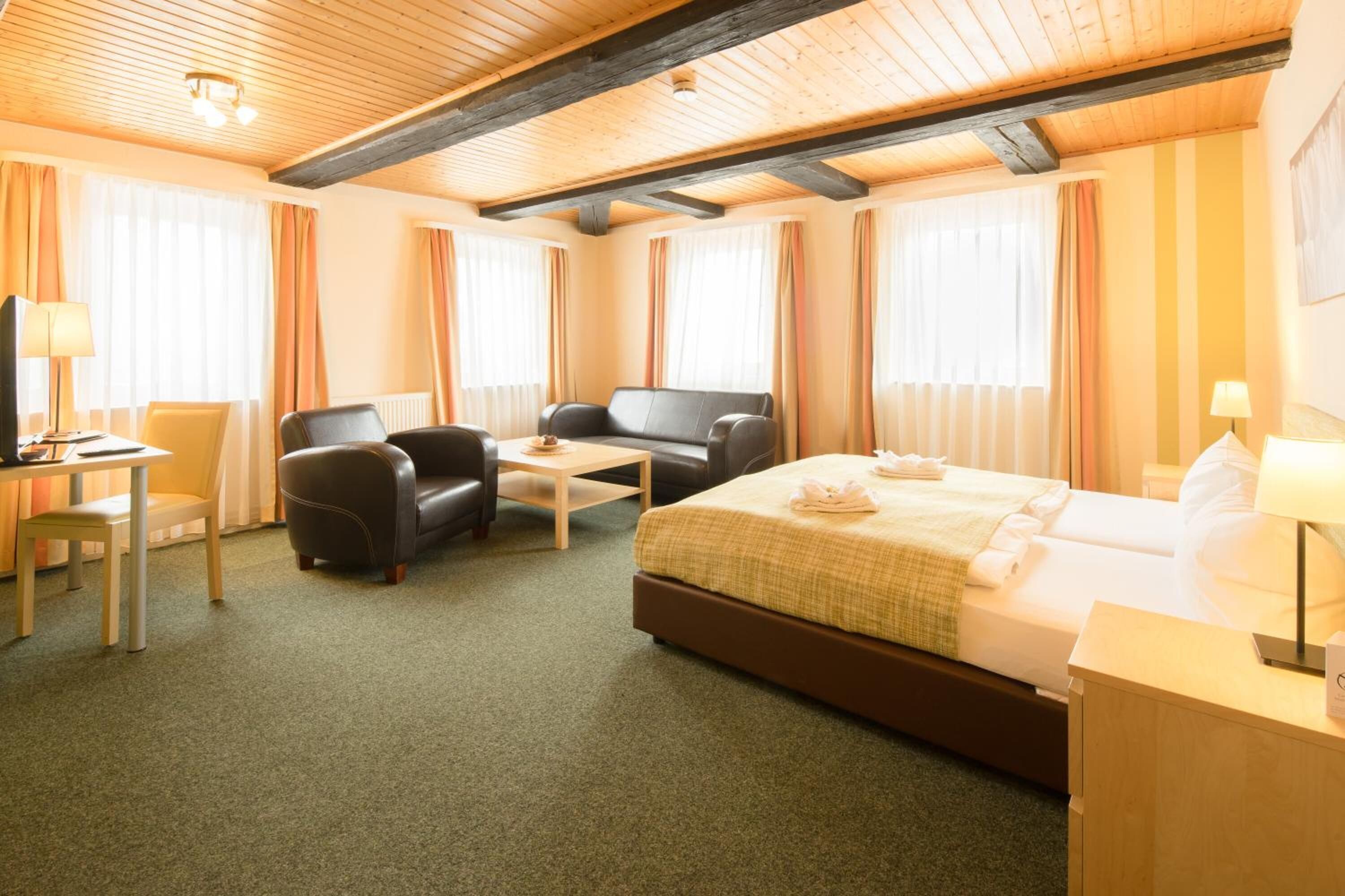 A hotel room with a bed, a sofa, a desk, and a chair.