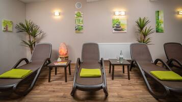 Relax in a serene spa room with three reclining chairs, a small table, and soothing artwork.