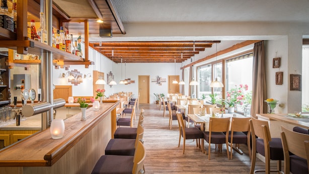 A restaurant with wooden furniture, a bar area, and large windows. - AKZENT Hotel Haus Sonnenberg (Schotten)