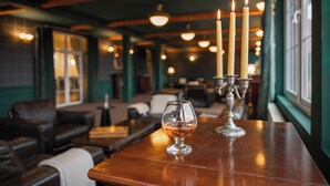 A bar area with a glass of whiskey, candles, and leather seating. - Monterai Resort (Brasov)