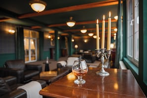 A bar area with a glass of whiskey, candles, and leather seating. - Monterai Resort (Brasov)