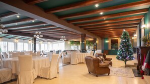 A spacious hall with round tables and chairs, a Christmas tree, and a fireplace. - Monterai Resort (Brasov)