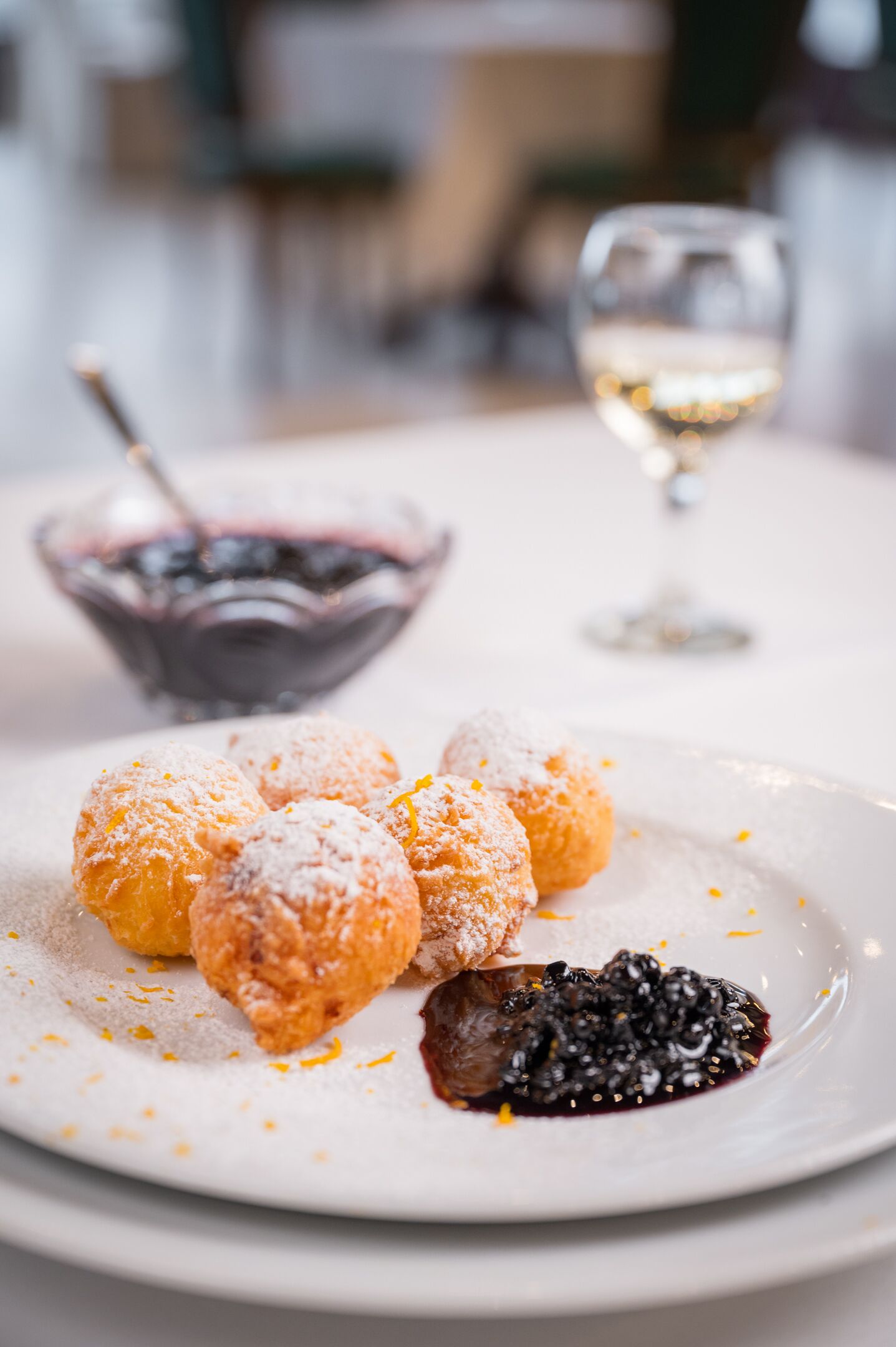 A plate of powdered doughnuts with a berry compote on a white plate.