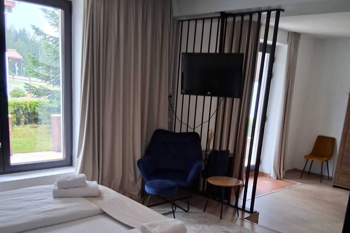 A hotel room with two beds, a TV, a blue chair, and a small table.