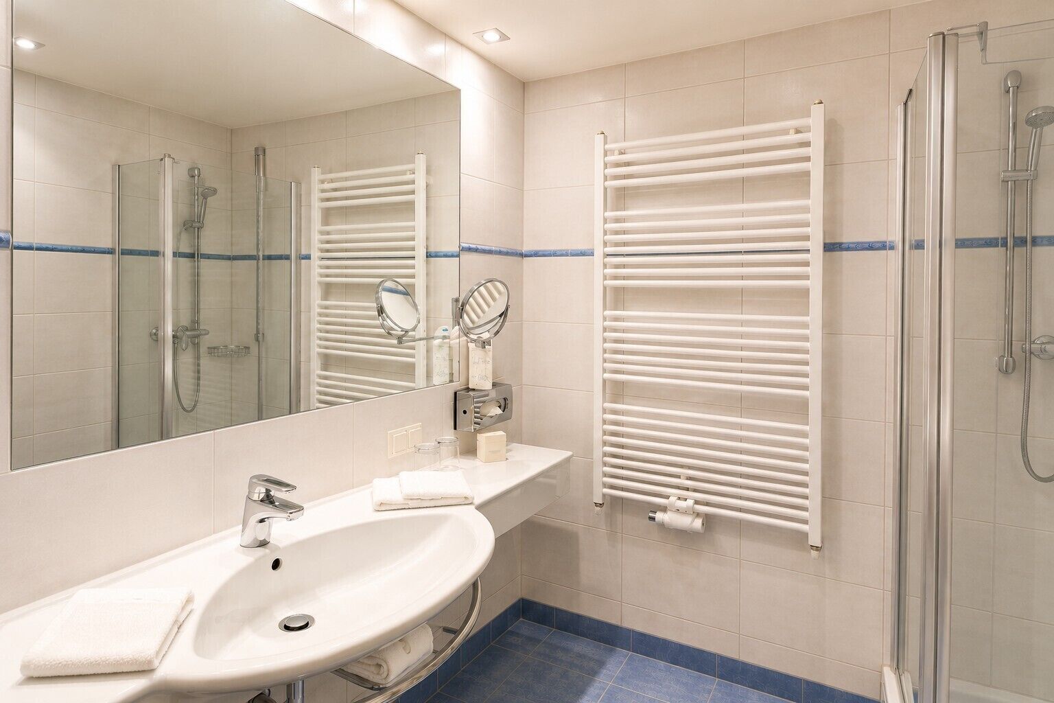 A bathroom with a sink, mirror, towel rack, and shower.