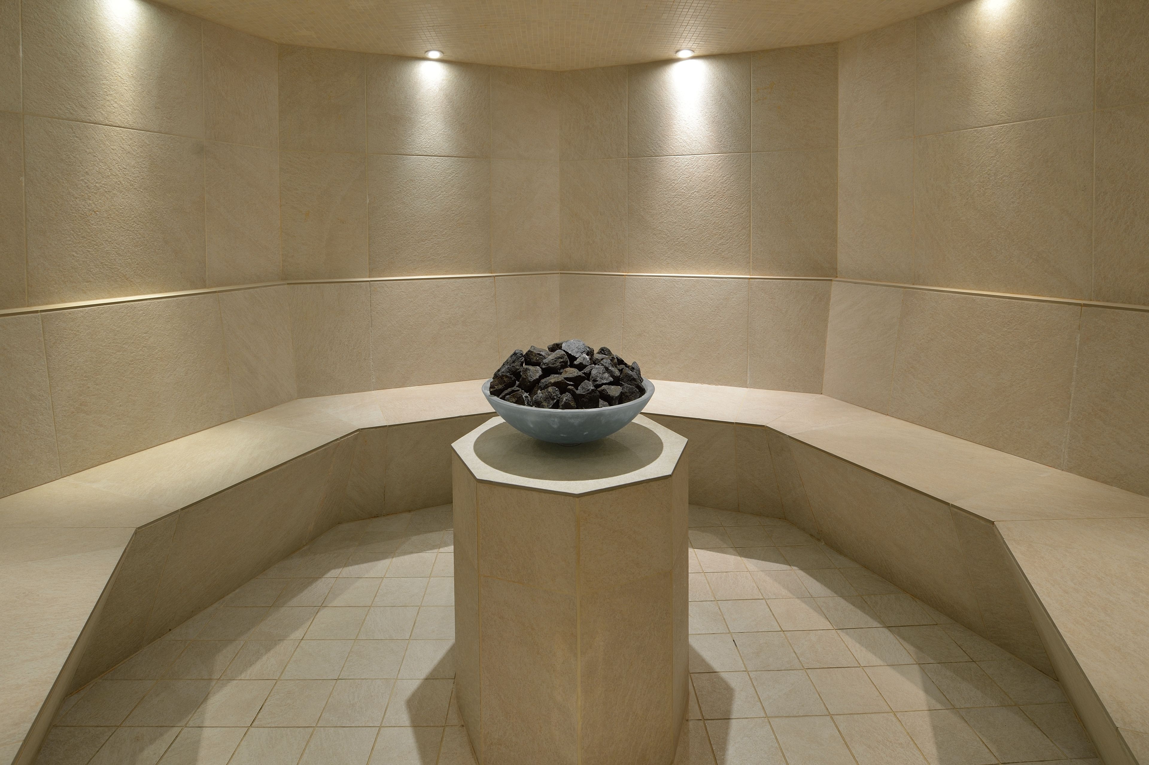 A spa area with a stone bench and a bowl of stones.