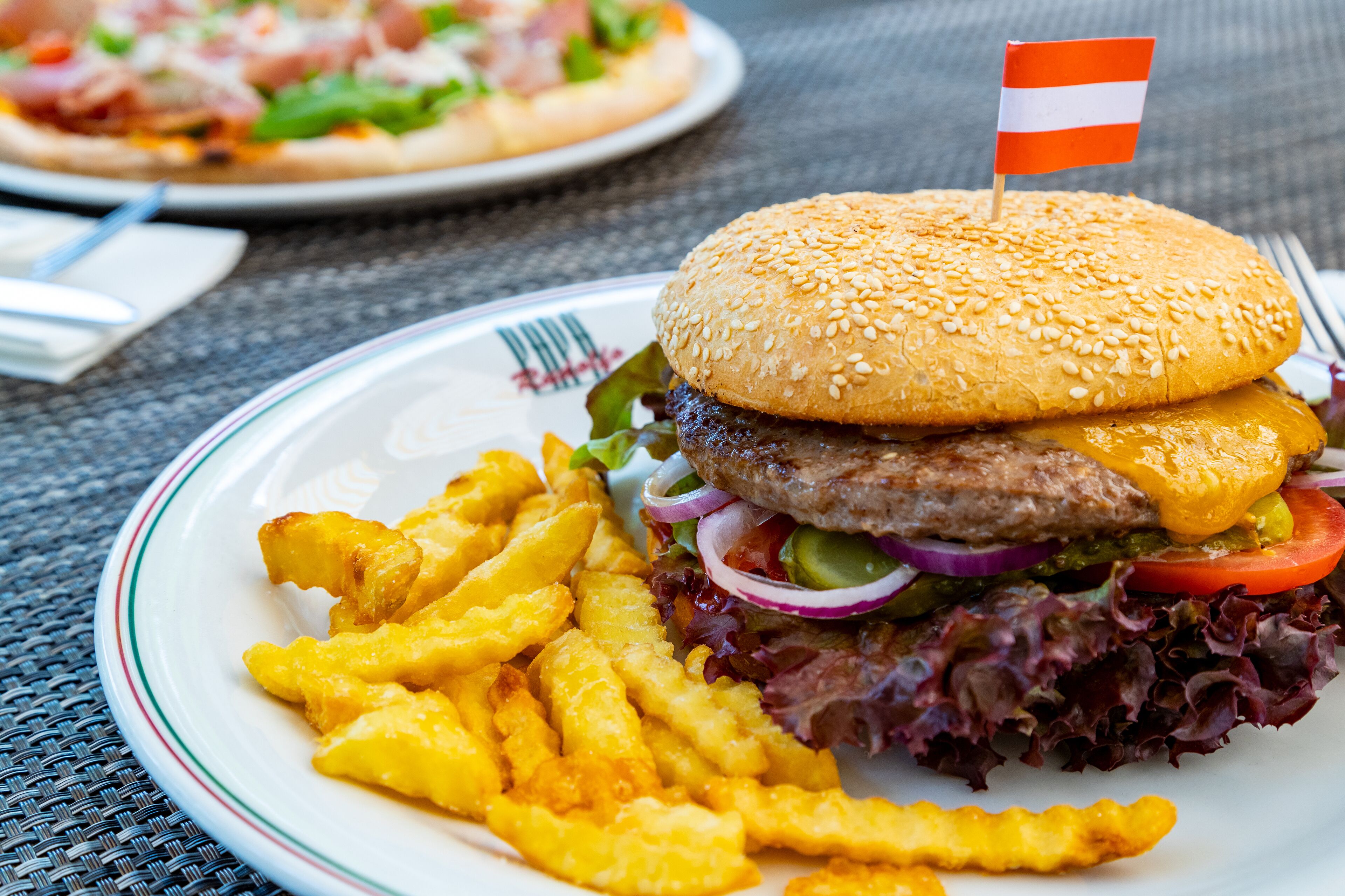 A plate with a hamburger, fries, and a flag.
