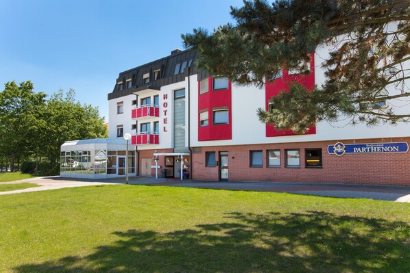 Un hôtel au design moderne, doté d’une entrée en verre et d’une façade rouge et blanche.