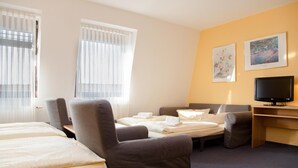 Una habitación de hotel con dos camas, un escritorio, un televisor y dos cuadros en la pared.