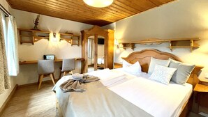 A hotel room with a wooden ceiling, a bed with white bedding, a desk with a chair, and a mirror. - Naturhotel Gasthof Bärenfels (Altenberg)