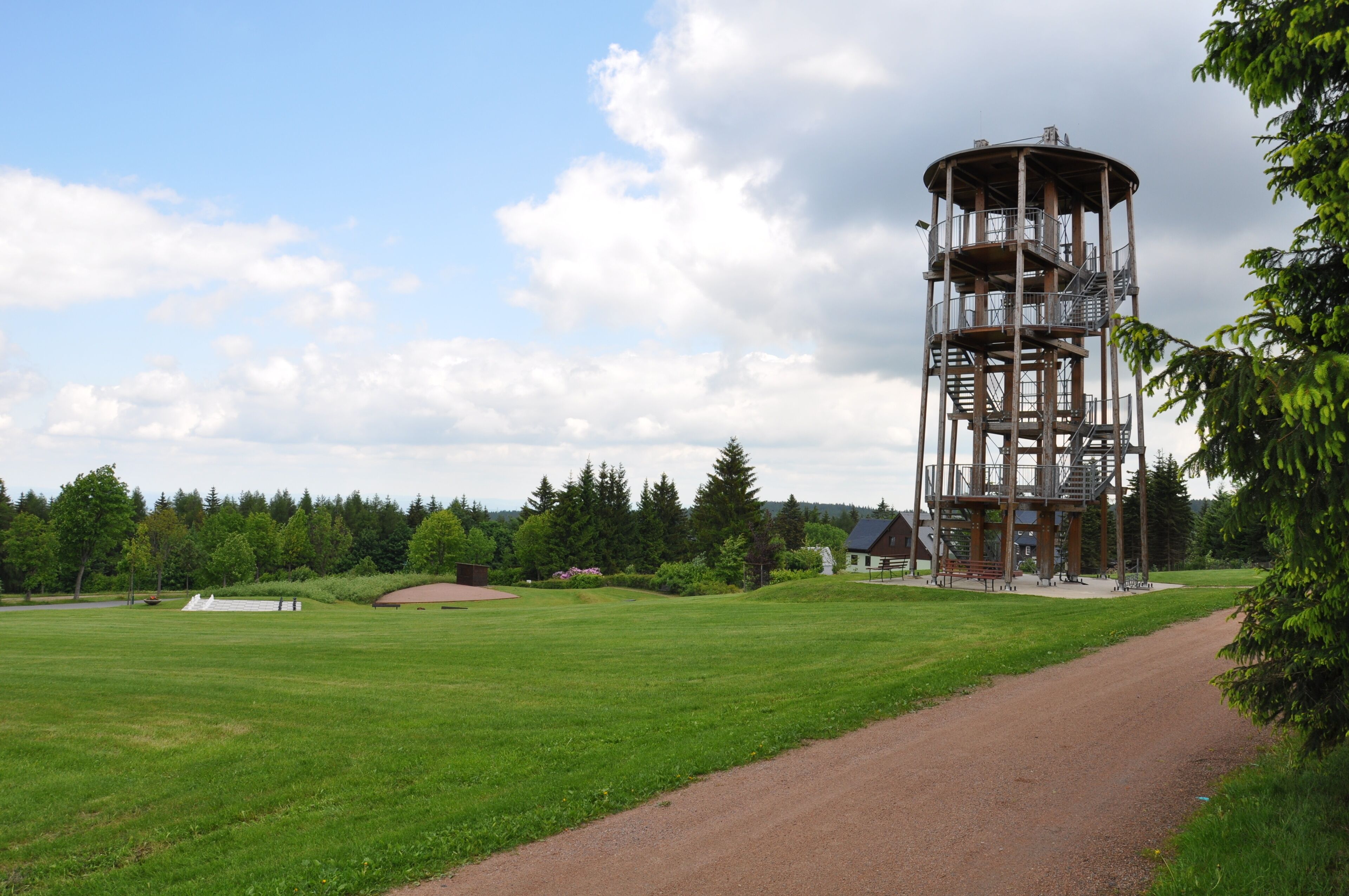 A tower structure with multiple levels and a surrounding grassy field.