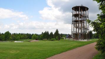A tower structure with multiple levels and a surrounding grassy field.