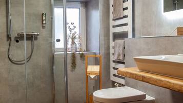 Un baño moderno con cabina de ducha de vidrio, tocador de madera y un espejo grande.