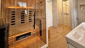 A modern bathroom with a glass shower enclosure, wooden flooring, and a white bathtub. - Naturhotel Gasthof Bärenfels (Altenberg)
