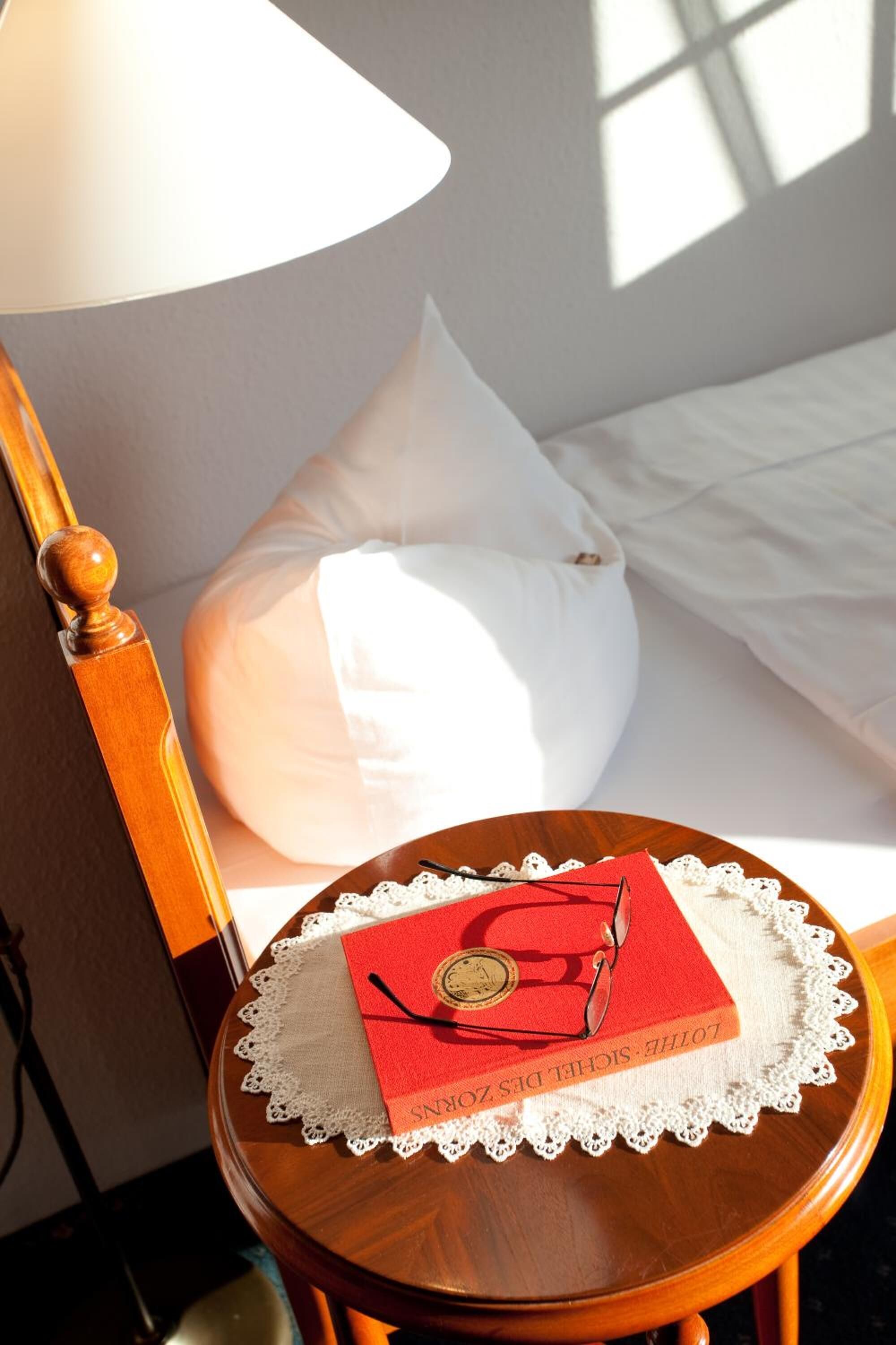 A wooden chair with a lace doily and a red book titled "Lotte S. Zorn" on it.