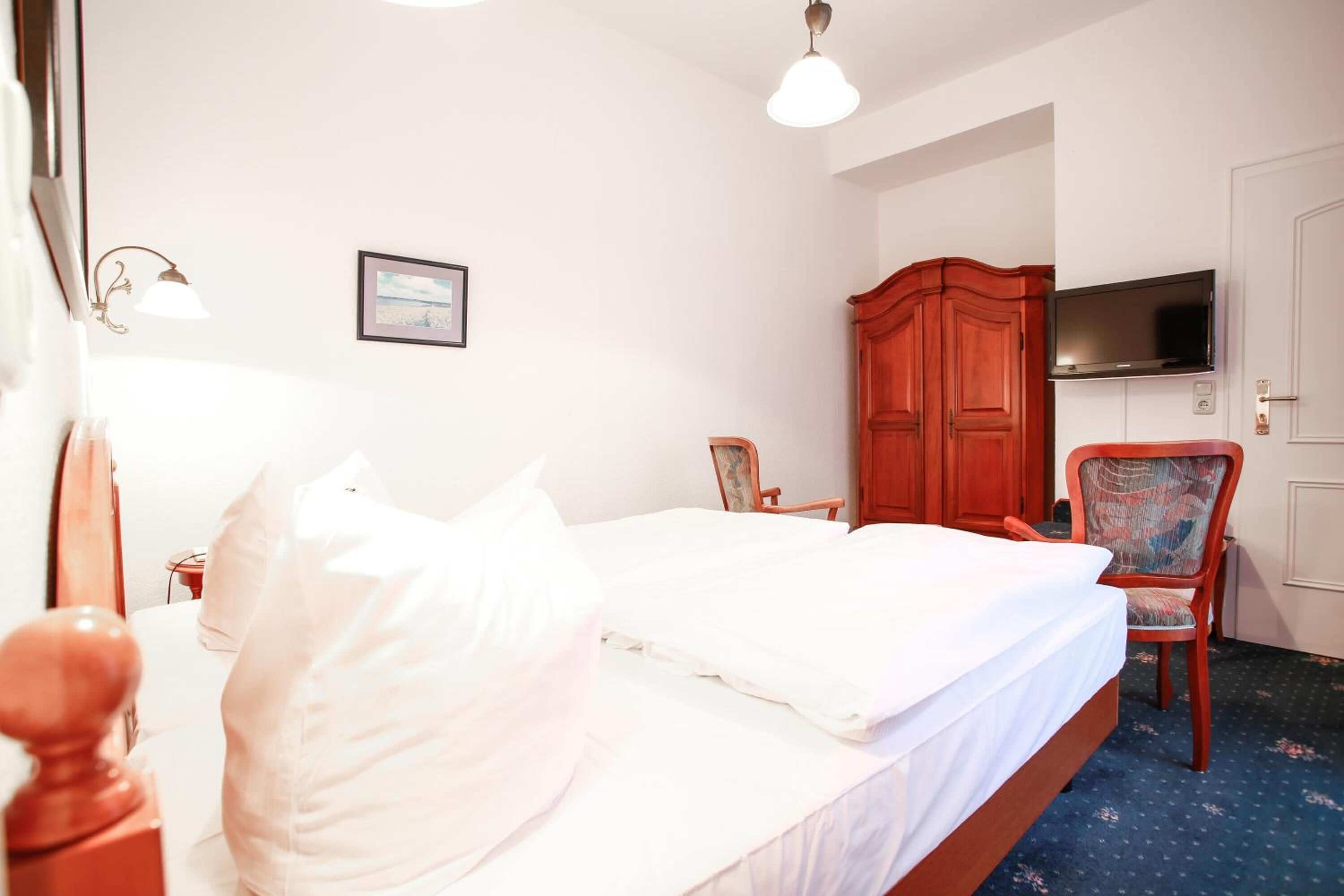 Une chambre d’hôtel avec un lit, une télévision, une armoire et une chaise.