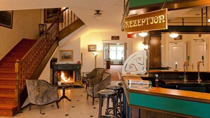 A reception area with a staircase, a fireplace, and bar stools. - Hotel Stranddistel Rügen (Göhren)