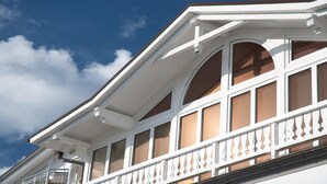 A building with a white facade, multiple windows, and a balcony with a white balustrade. - Hotel Stranddistel Rügen (Göhren)