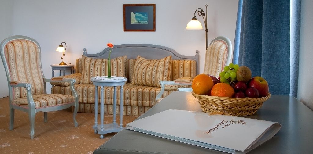Una sala de estar acogedora con un sofá, dos sillones, una mesita y una cesta de frutas.